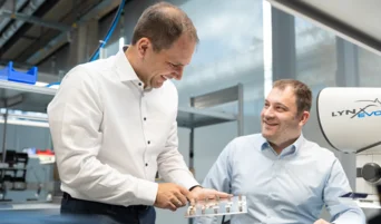 Engineers inspecting miniature force torque sensor components in lab with microscope system visible 
