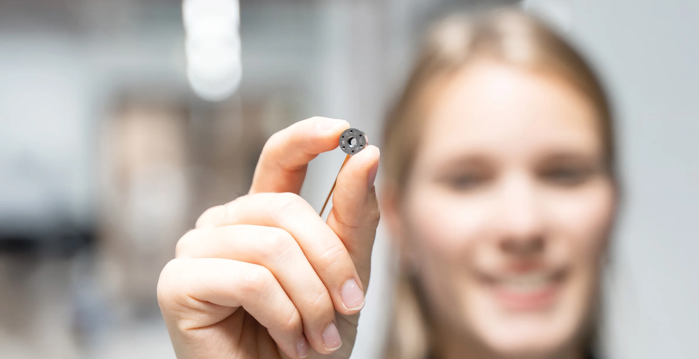 Miniature 6 axis force torque sensor held between fingers highlighting compact design and precision