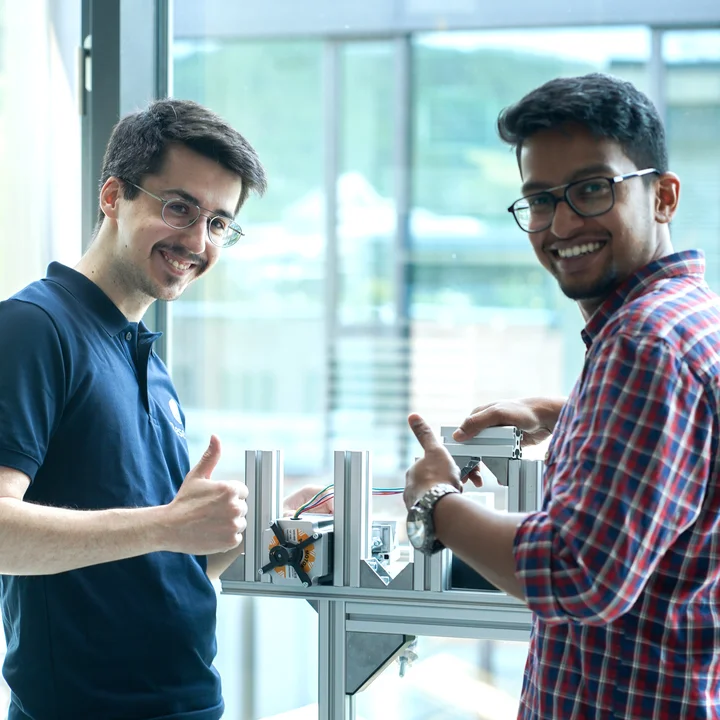 Two engineers working on robotic test setup with mounted components and control electronics